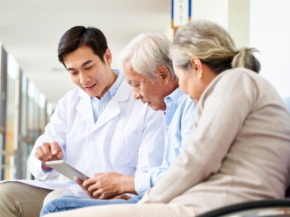 Doctor showing medical information on a tablet to elderly patients during a consultation